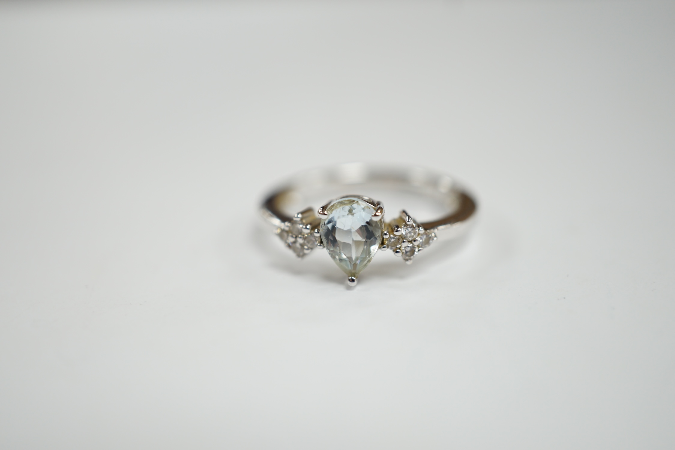 A modern Italian Comete 18k white metal and single stone pear cut aquamarine set ring, with eight stone diamond cluster set shoulders, size N, gross weight 3.3 grams.